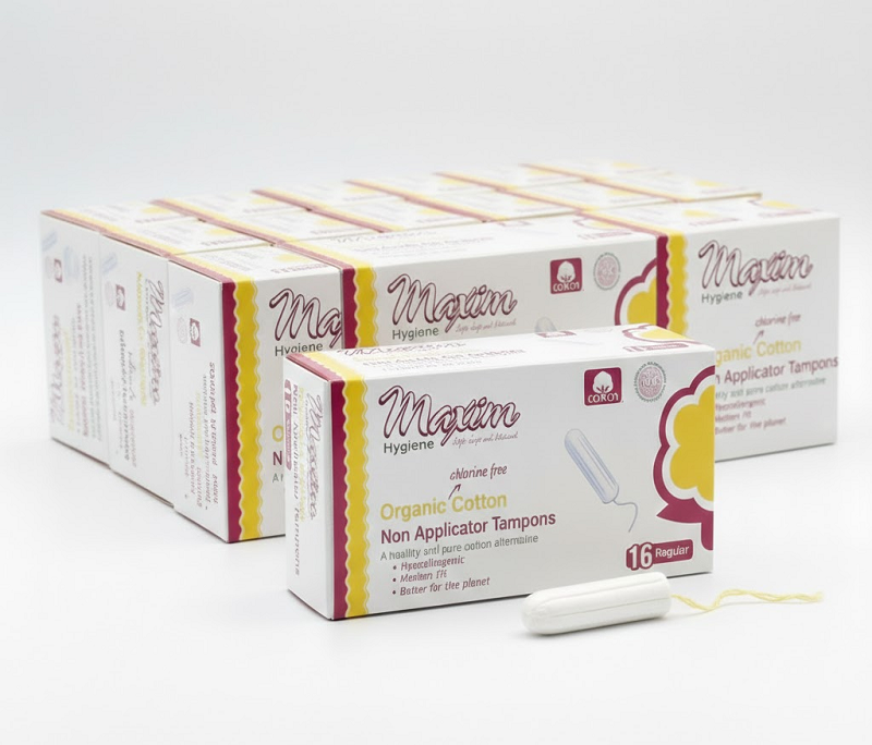 Maxim Hygiene organic cotton non-applicator tampons (16 regular) multi-pack boxes shown with a tampon and yellow string, highlighting chlorine-free, hypoallergenic period protection with reduced-waste packaging.