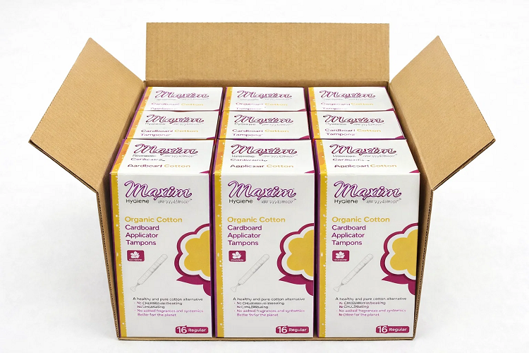 Open shipping case of Maxim Hygiene organic cotton cardboard applicator tampons, 16 regular-count boxes arranged in a cardboard carton on a white background.