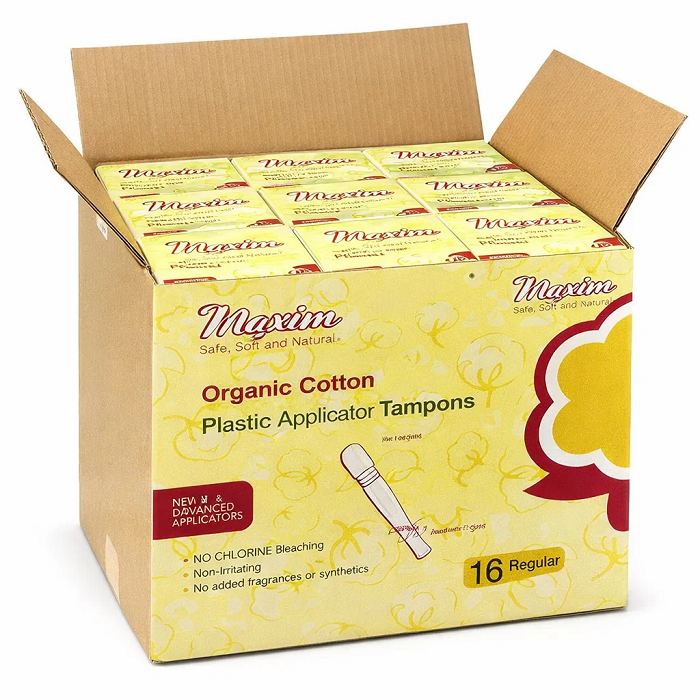 Bulk case of Maxim organic cotton plastic applicator tampons (16 regular per box) with an open carton showing multiple retail packs, chlorine-free and fragrance-free period care.