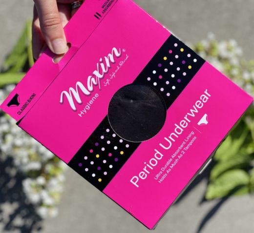 Hand holding Maxim period underwear classic bikini package in pink with medium absorbency, reusable leak-proof menstrual underwear.