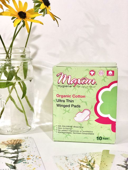 oman relaxing by a sunny window holding a cup of tea, with text “Designed to stay in place all day long,” conveying all-day comfort and secure fit for period care products.